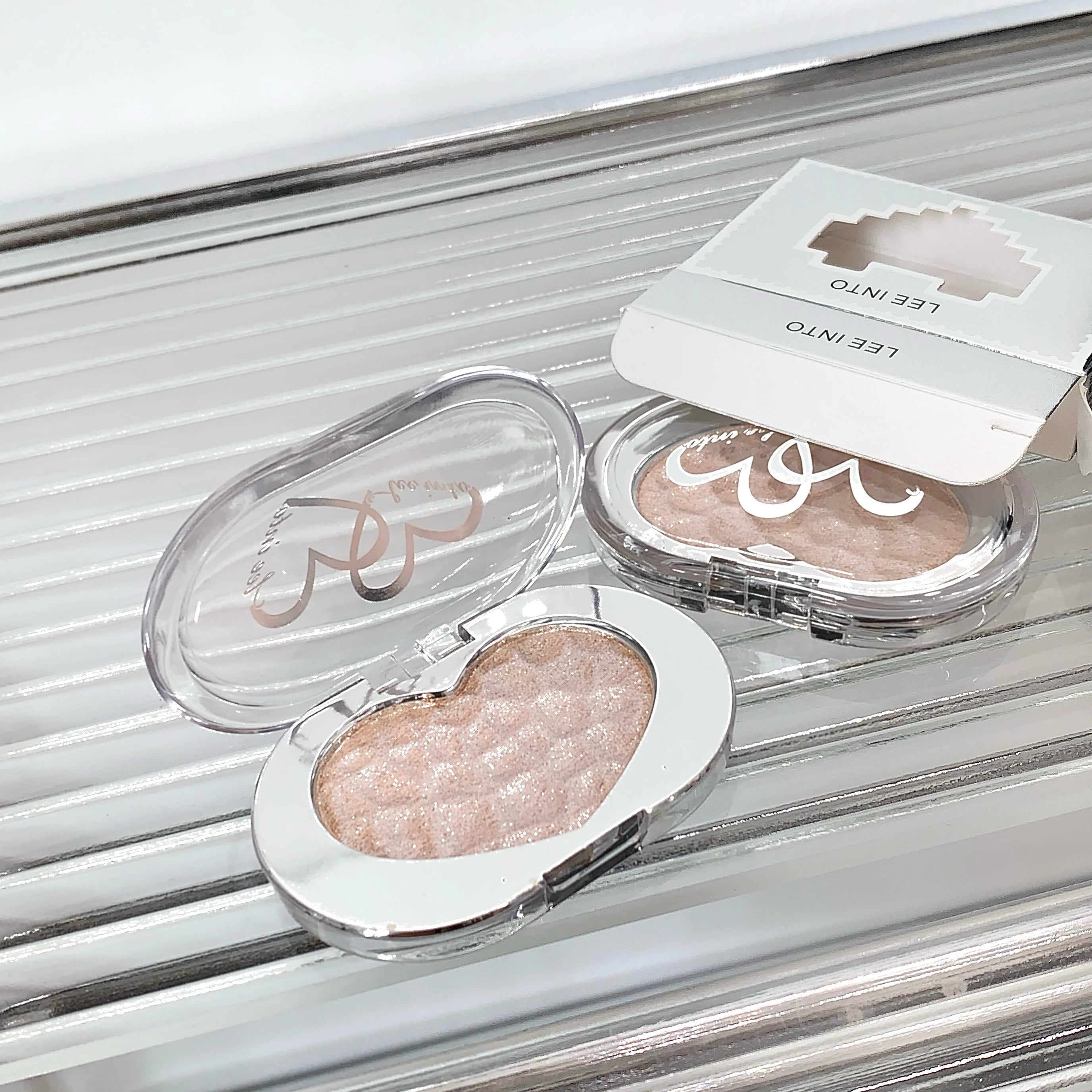 Tidesmit LEE INTO highlighting powder with pearlescent finish and silky texture in a detailed close-up view