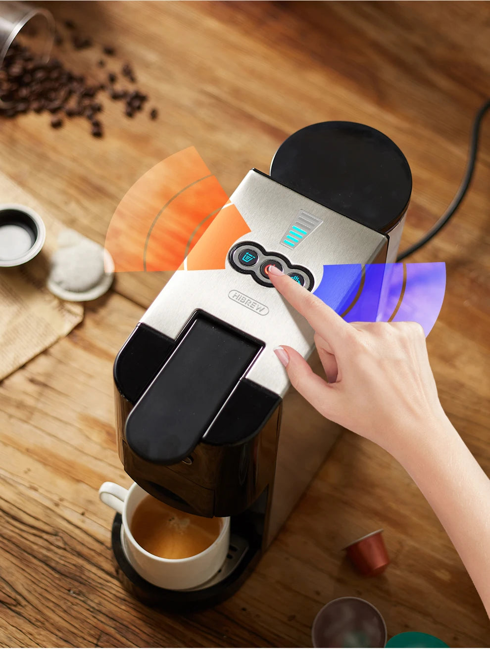 HiBREW silver and black capsule coffee machine brewing hot espresso on a wooden table with touch-control interface.