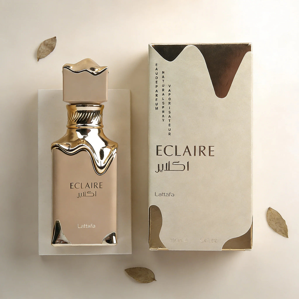 Lattafa Eclaire perfume bottle and box with gold metallic drip design on a beige background with autumn leaves.
