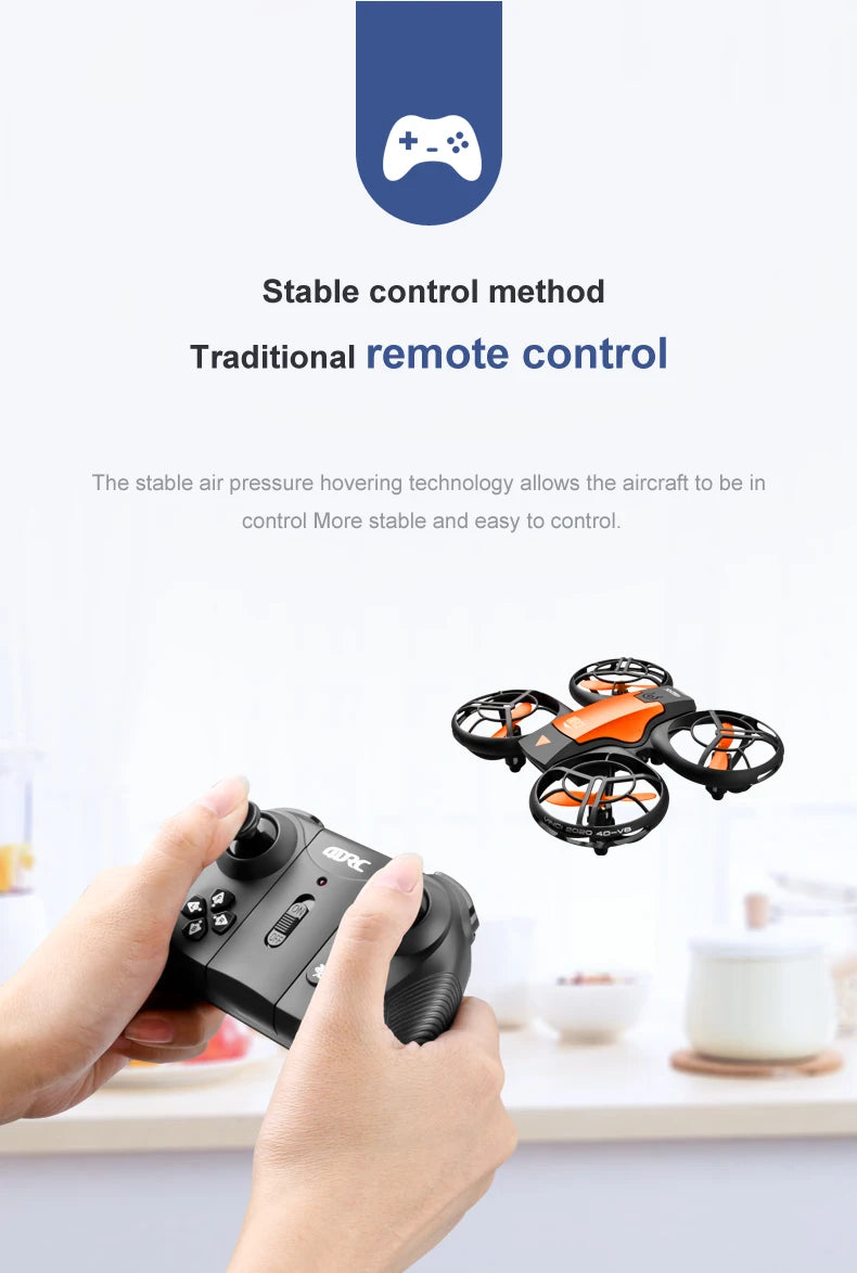 Small black and orange remote-controlled quadcopter drone with protective blade guards, operated by a handheld