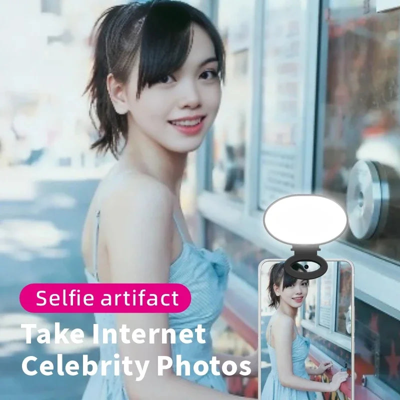 Small oval clip-on LED phone light in black, providing illumination for taking selfies and portrait photography.