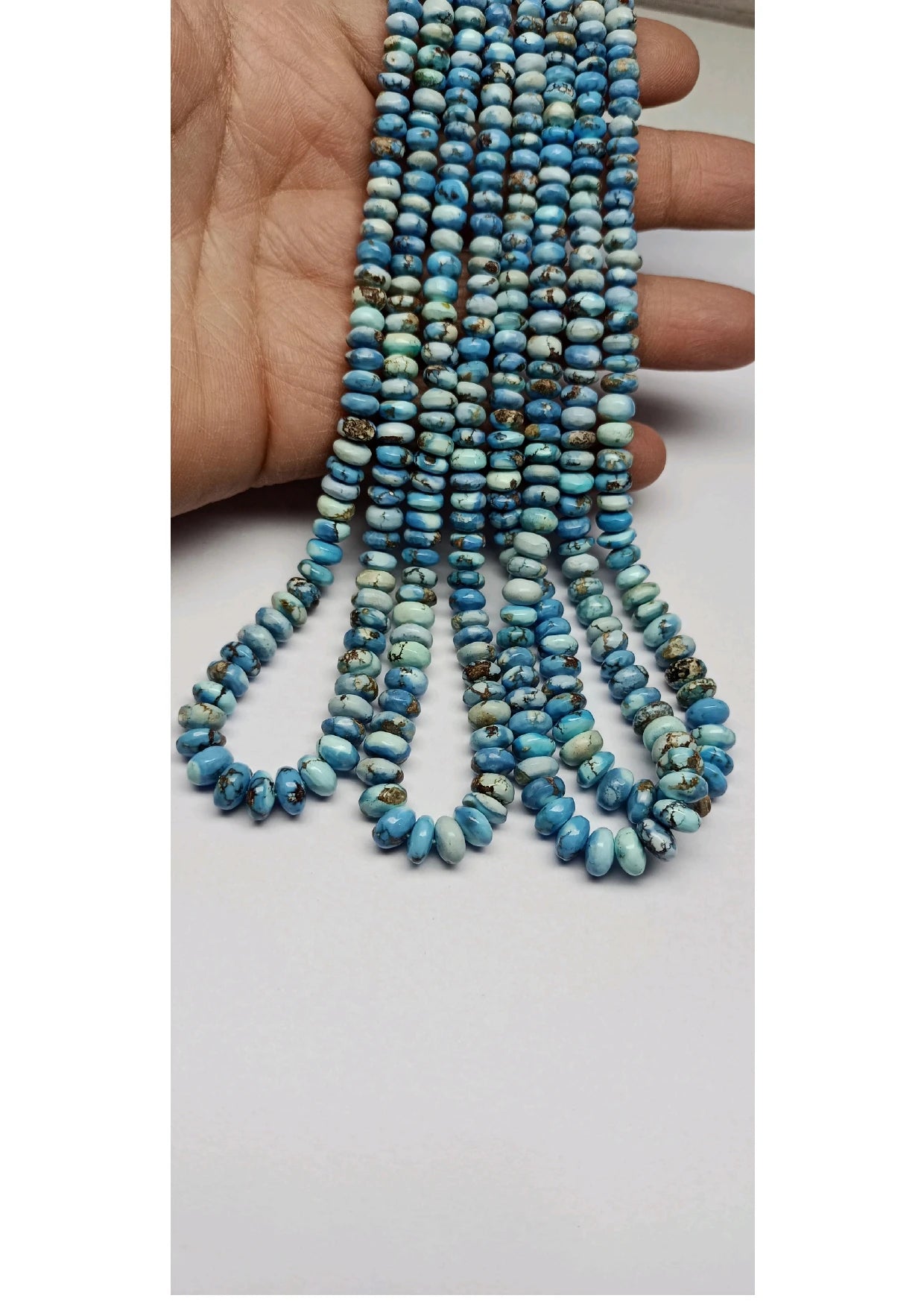 Turquoise rondelle bead strand in hand, smooth beads forming tassel fringe