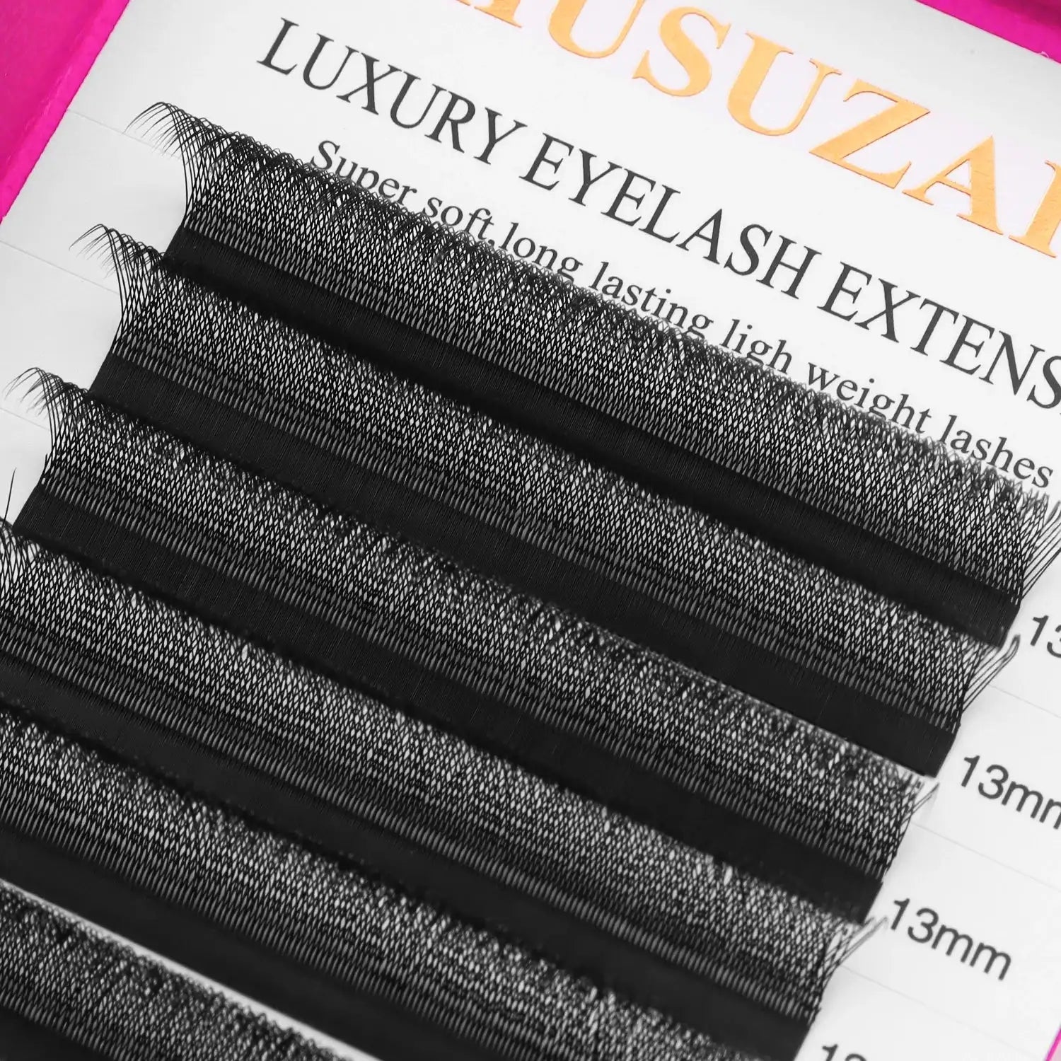 Tray of 13mm black synthetic eyelash extensions arranged in parallel rows for professional application.
