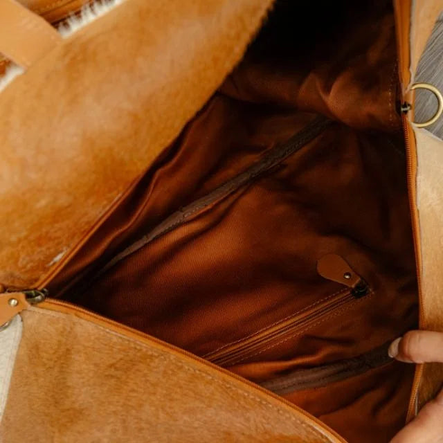 Tan genuine leather Western duffel trunk with brown fabric interior, zippered pocket, and unique embossed details.