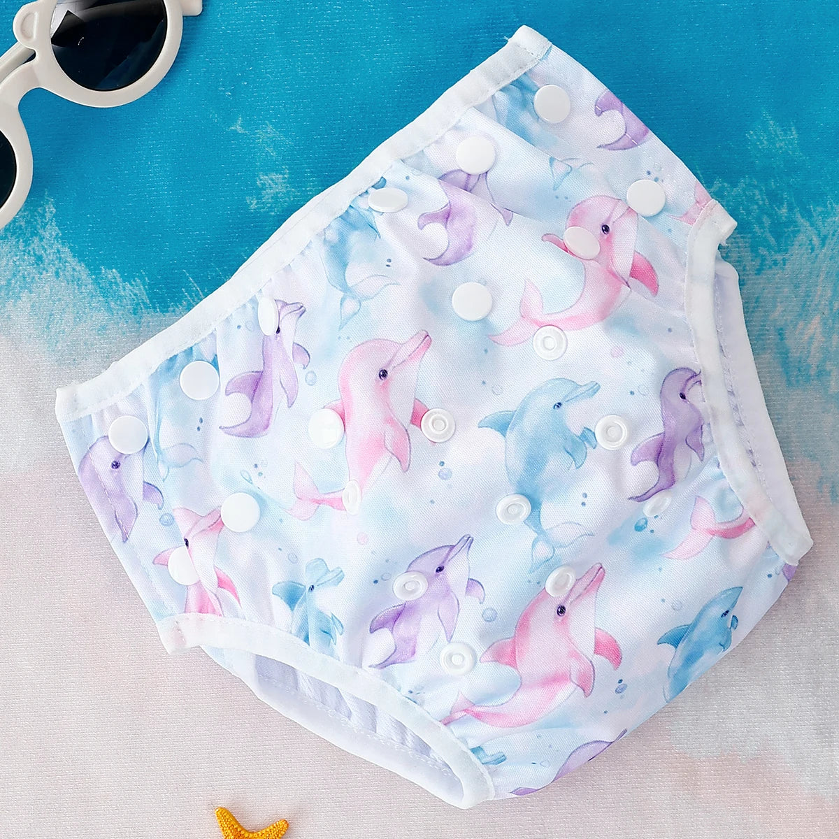 Reusable dolphin print baby swim diaper with adjustable snaps for a comfortable fit.