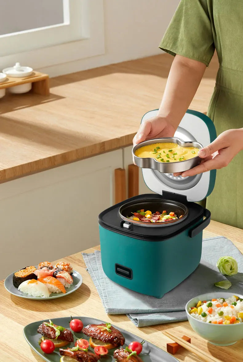 Teal mini electric rice cooker on kitchen counter with lid open and food inside
