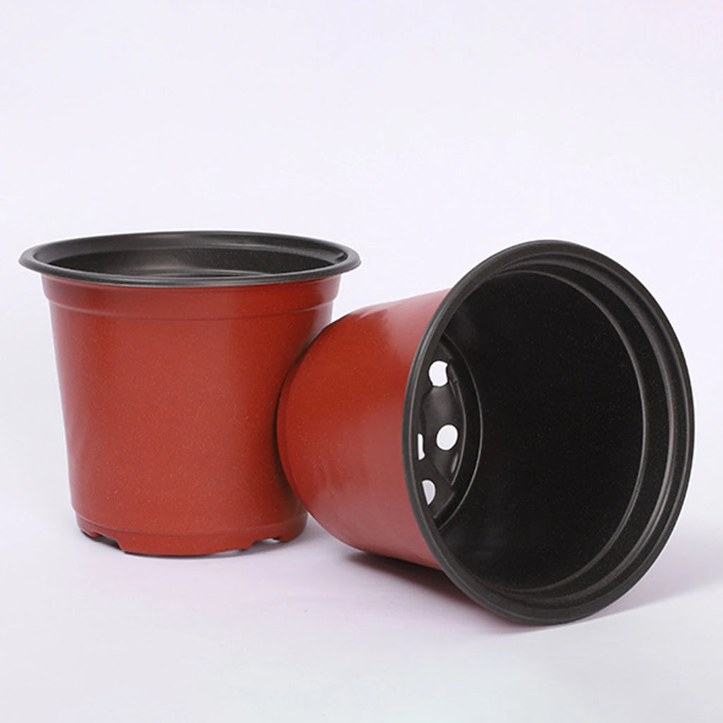 Pair of red plastic plant pots with black interiors and drainage base, side view