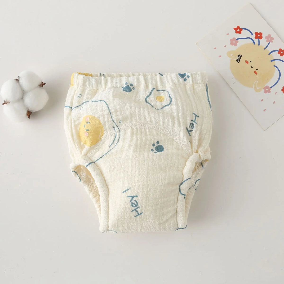 Baby care training diaper in cream cotton with egg and paw print design.