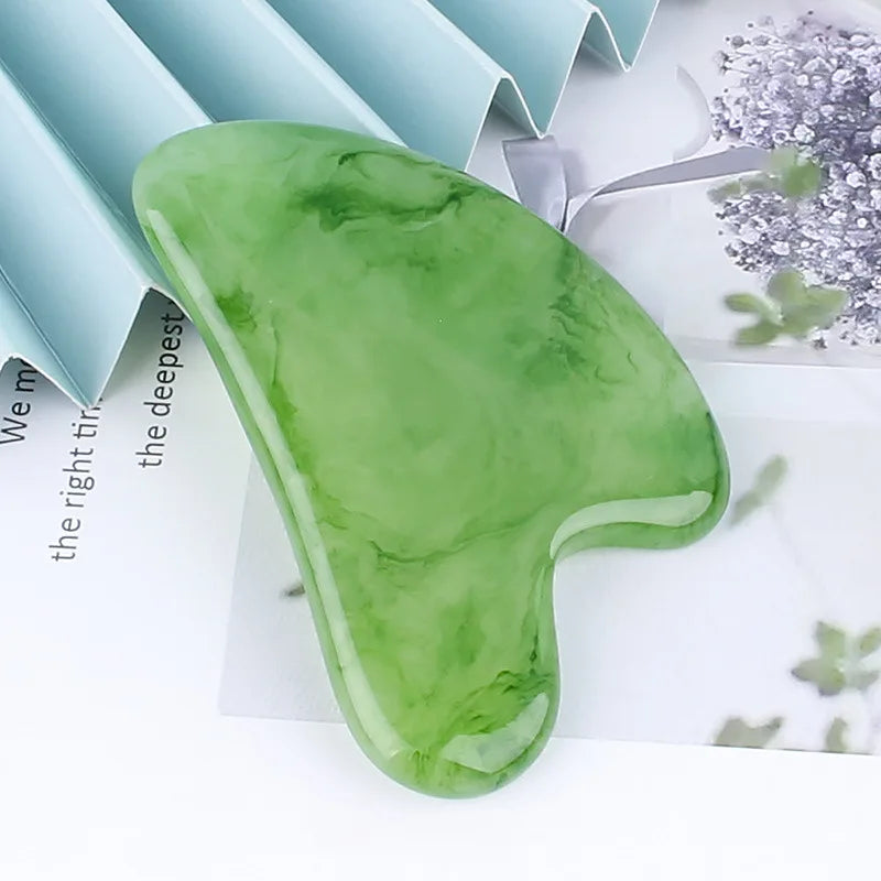 Green, heart-shaped resin gua sha facial massage tool with a smooth, marbled texture.