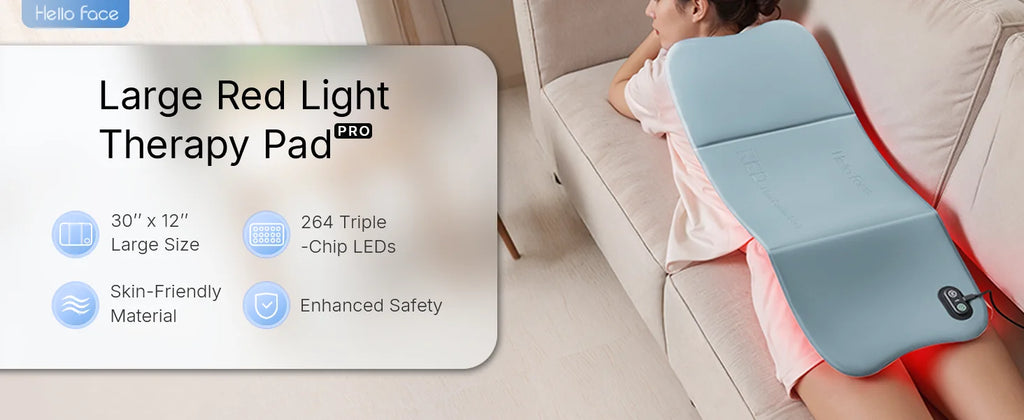 A woman lies on a couch with a large, light blue Hello Face red light therapy mat placed across her lower back.