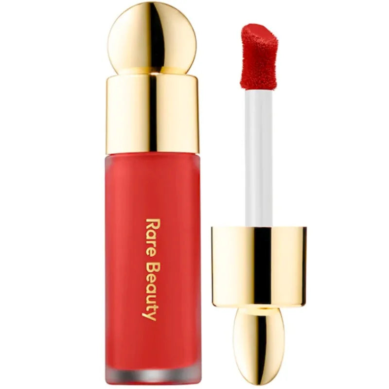 Rare Beauty matte liquid lipstick in vibrant red with a smooth doe-foot applicator and elegant gold cap.