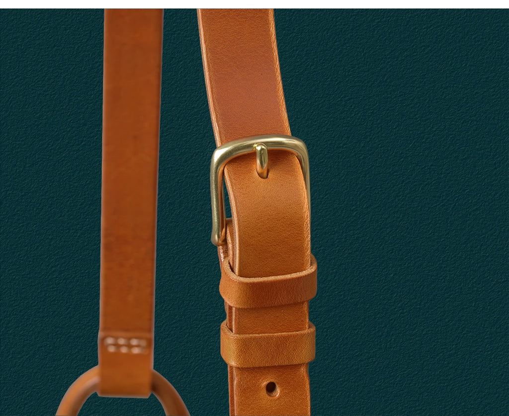 Tan genuine cowhide leather shoulder strap with a vintage-style brass buckle on a designer messenger bag.