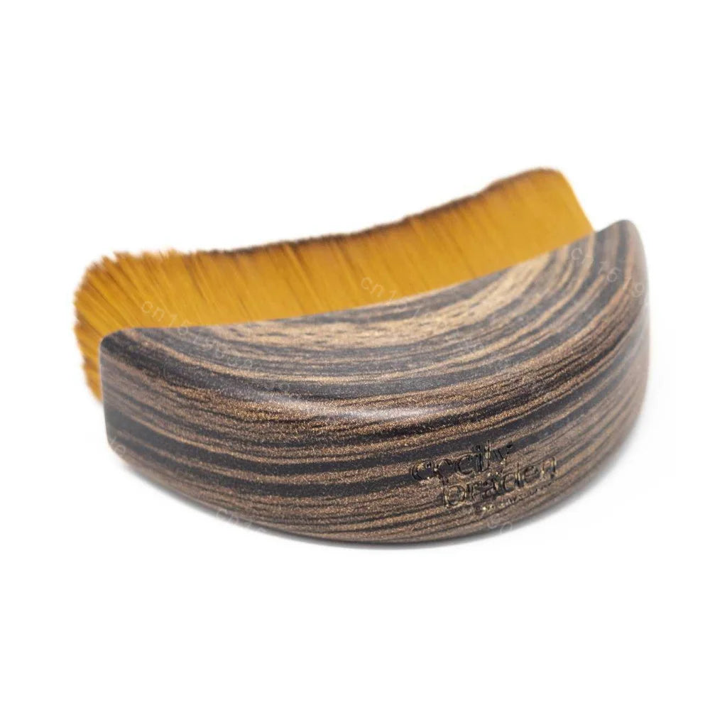 Curved lymphatic face brush with brown wood-grain handle and dense, golden-brown bristles on a white background.