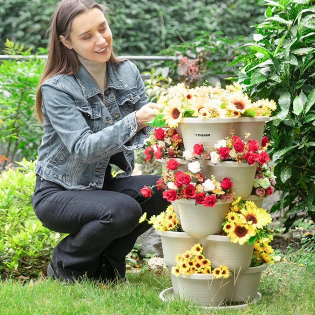 White stackable butterfly planter tower with tiered pots outdoors beside garden plants