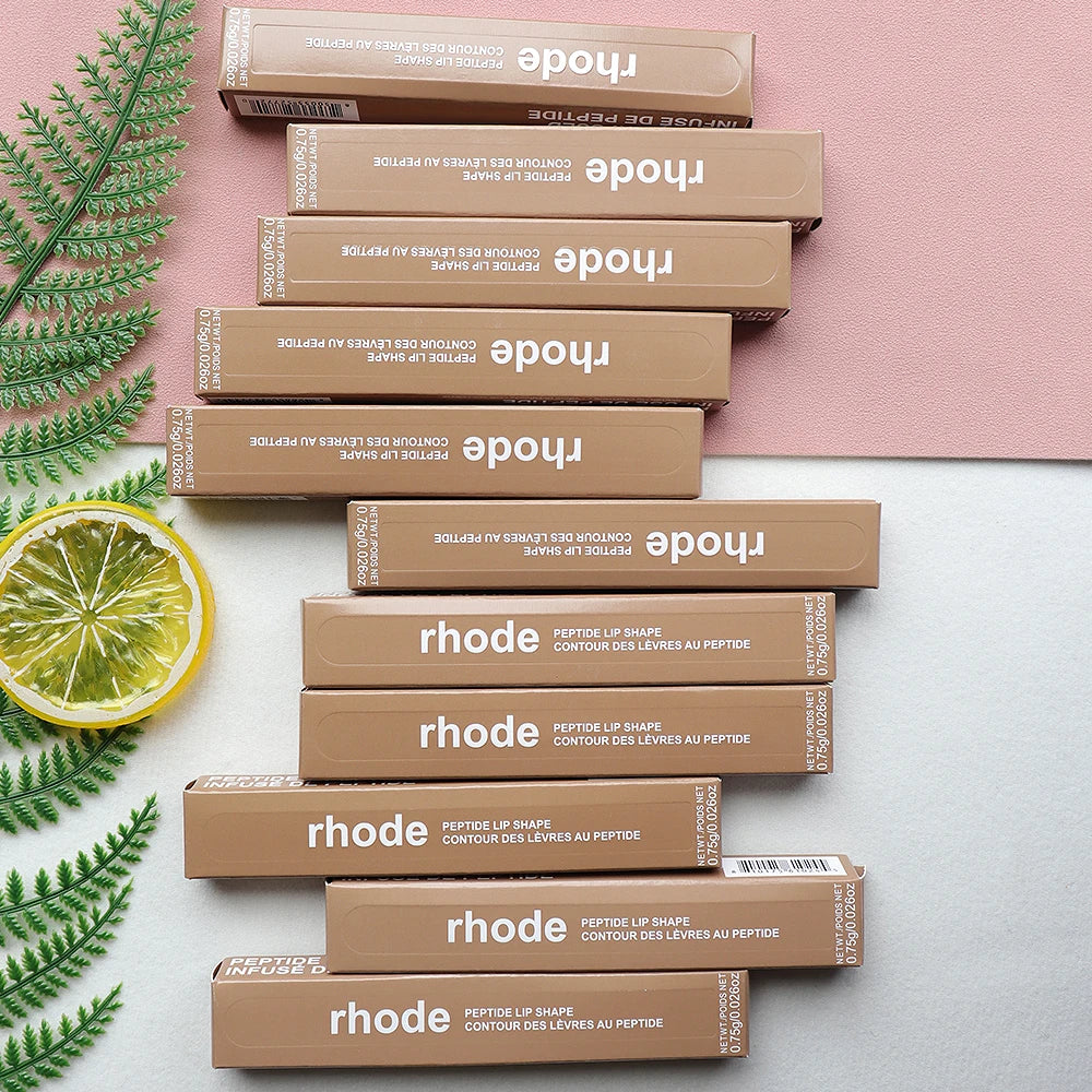 Stack of tan Rhode Peptide Lip Shape lip liner pencils in rectangular cardboard boxes on a decorative surface.