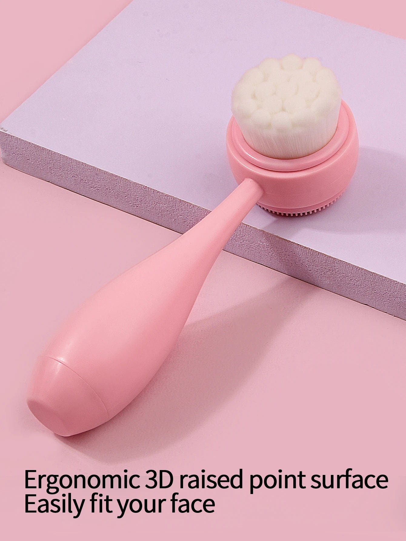 Pink handheld manual facial cleansing brush with soft white bristles for gentle makeup removal and skin exfoliation.