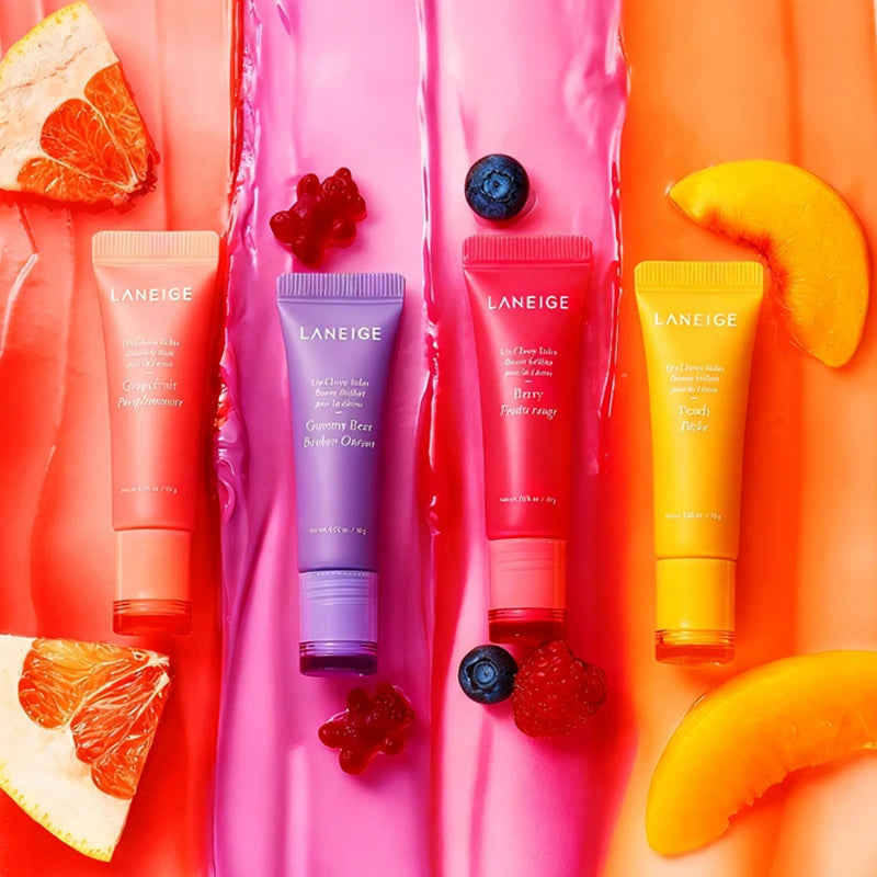 Laneige Lip Glowy Balm set in colorful fruit tubes on glossy, textured fruit-infused backgrounds for hydrated lips.