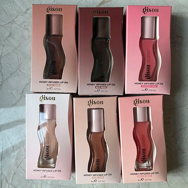 Six Gisou Honey Infused Lip Oil boxes in various shades, featuring a glossy, moisturizing, and plumping formula.