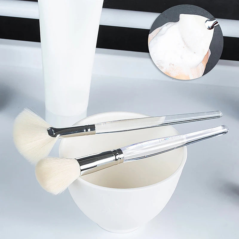 Soft facial cleanser brushes with clear handles in a bowl for applying face masks and deep pore skincare cleansing.