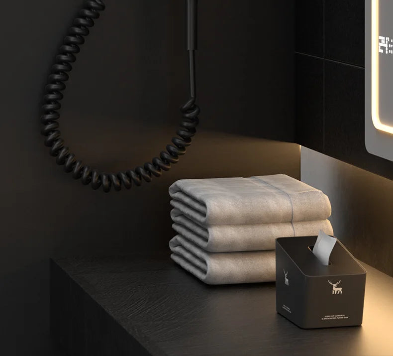 Matte black wall-mounted 1600W hotel hair dryer with coiled cord in a modern bathroom setup.