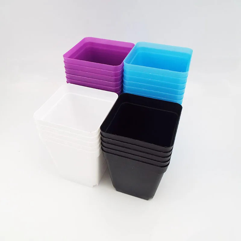 Small square plastic mini pots for succulents in white, black, purple, and blue, stacked together.
