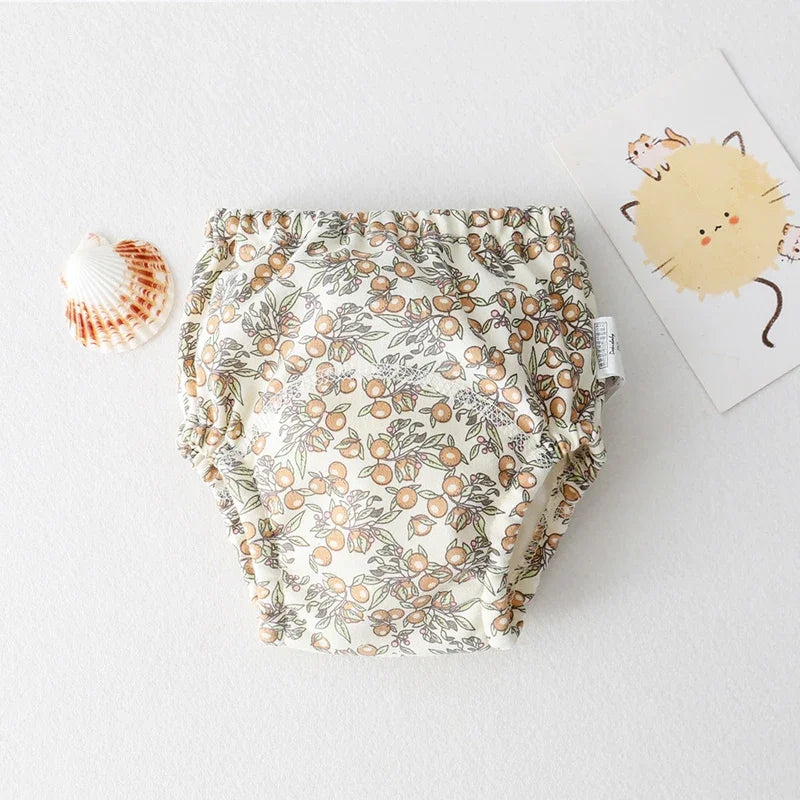 Baby care cloth diaper with orange fruit botanical print on cream fabric.