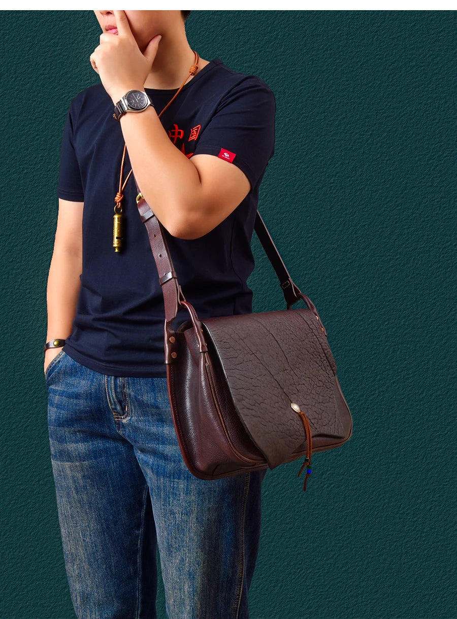 Vintage dark brown handmade cowhide leather messenger bag with textured flap, front button, and adjustable strap.