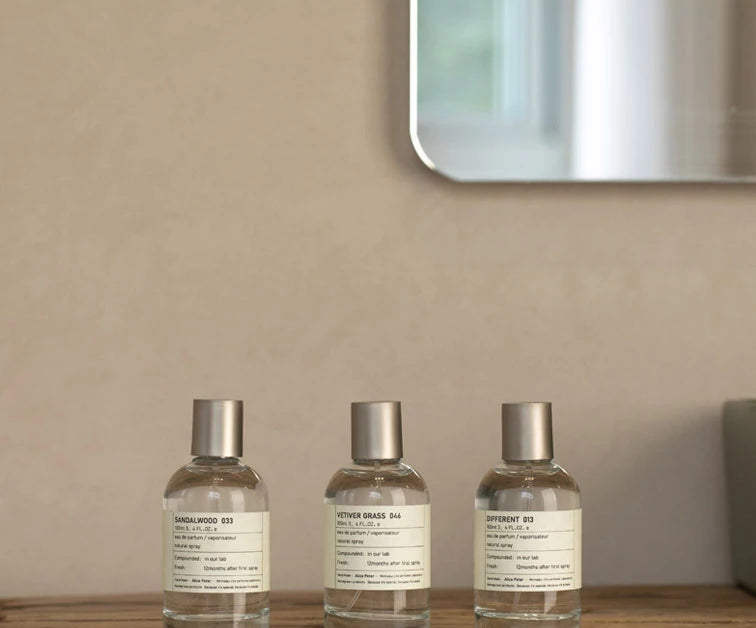 Alice Peter unisex sandalwood fruity Eau de Toilette 100ml in minimalist cylindrical glass bottles on wooden shelf.