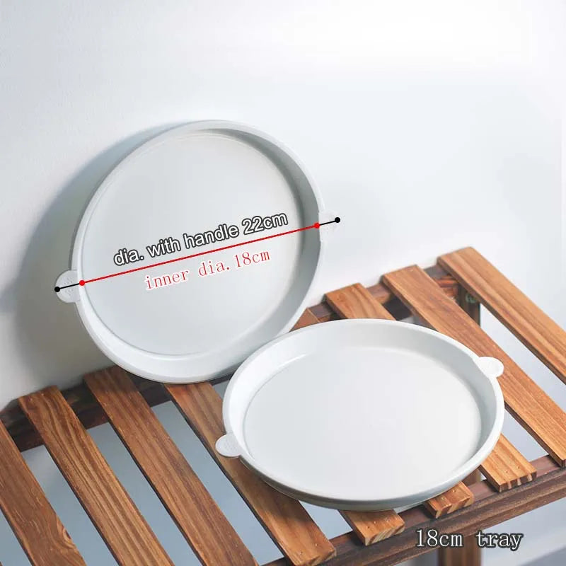 Round white plastic plant saucer trays with center handles, shown on a wooden stand.