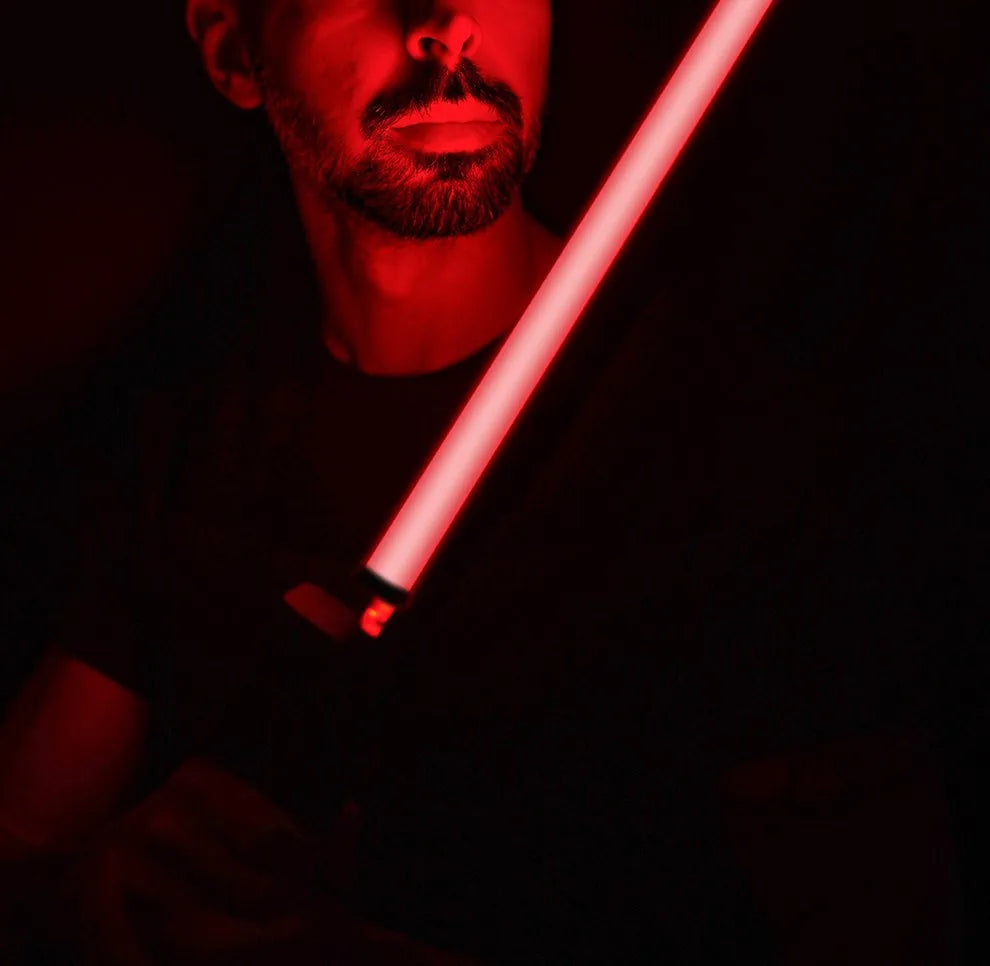 Man holding a glowing red LED light saber prop in a dark room.