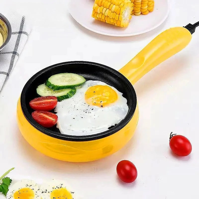 Yellow non-stick electric egg cooker with fried eggs and sliced vegetables in round pan.