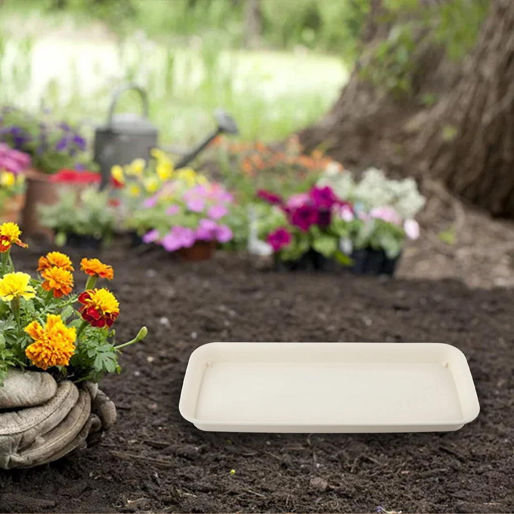 Beige rectangular plastic plant tray on garden soil beside flowers and stones
