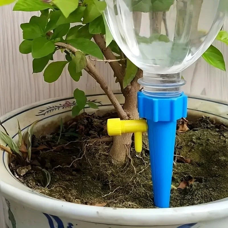 Blue automatic drip irrigation spike with yellow adjustment tip in potted soil.