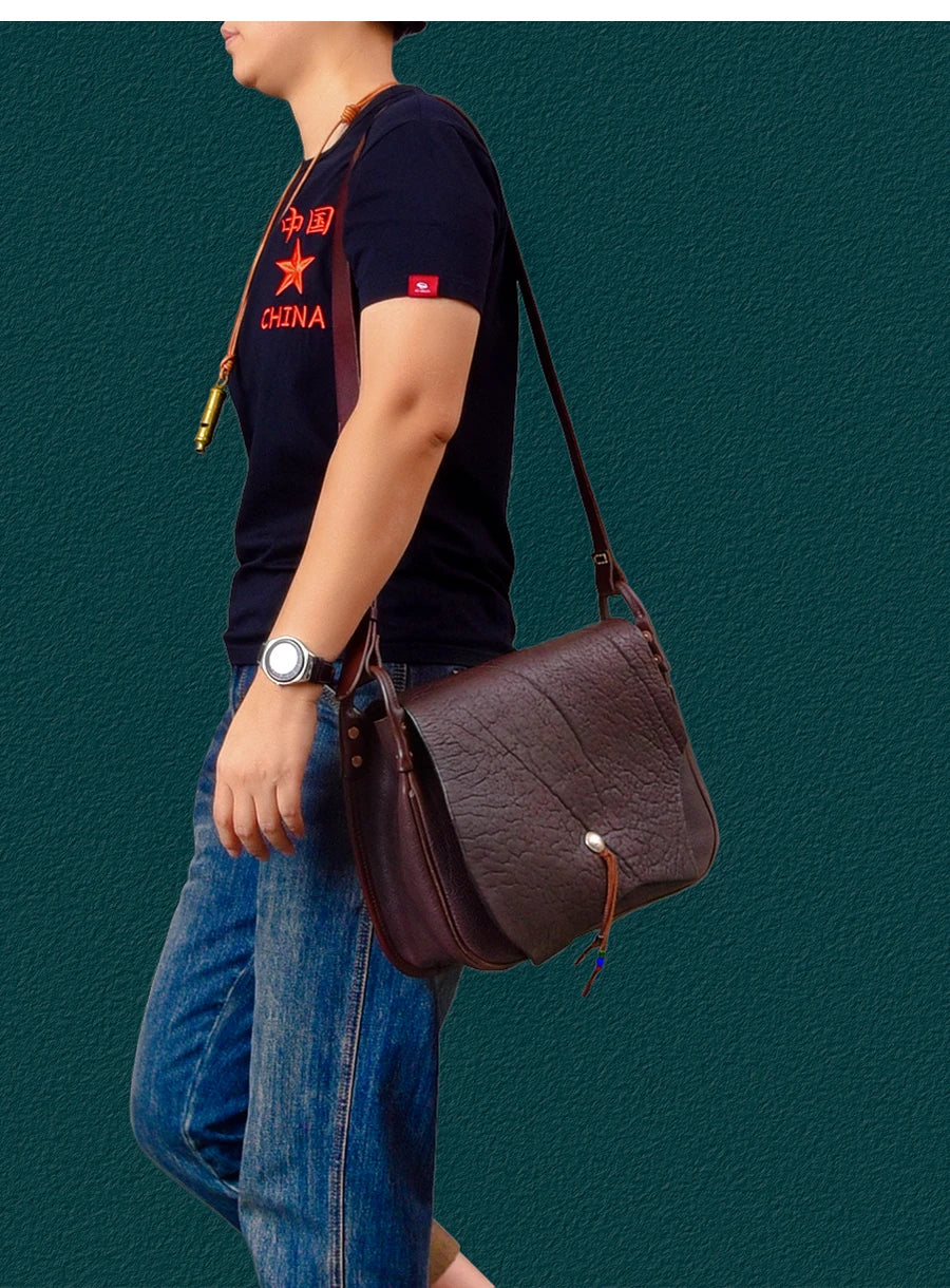 Vintage-style dark brown genuine cowhide leather messenger bag with a pebbled texture and button flap closure.