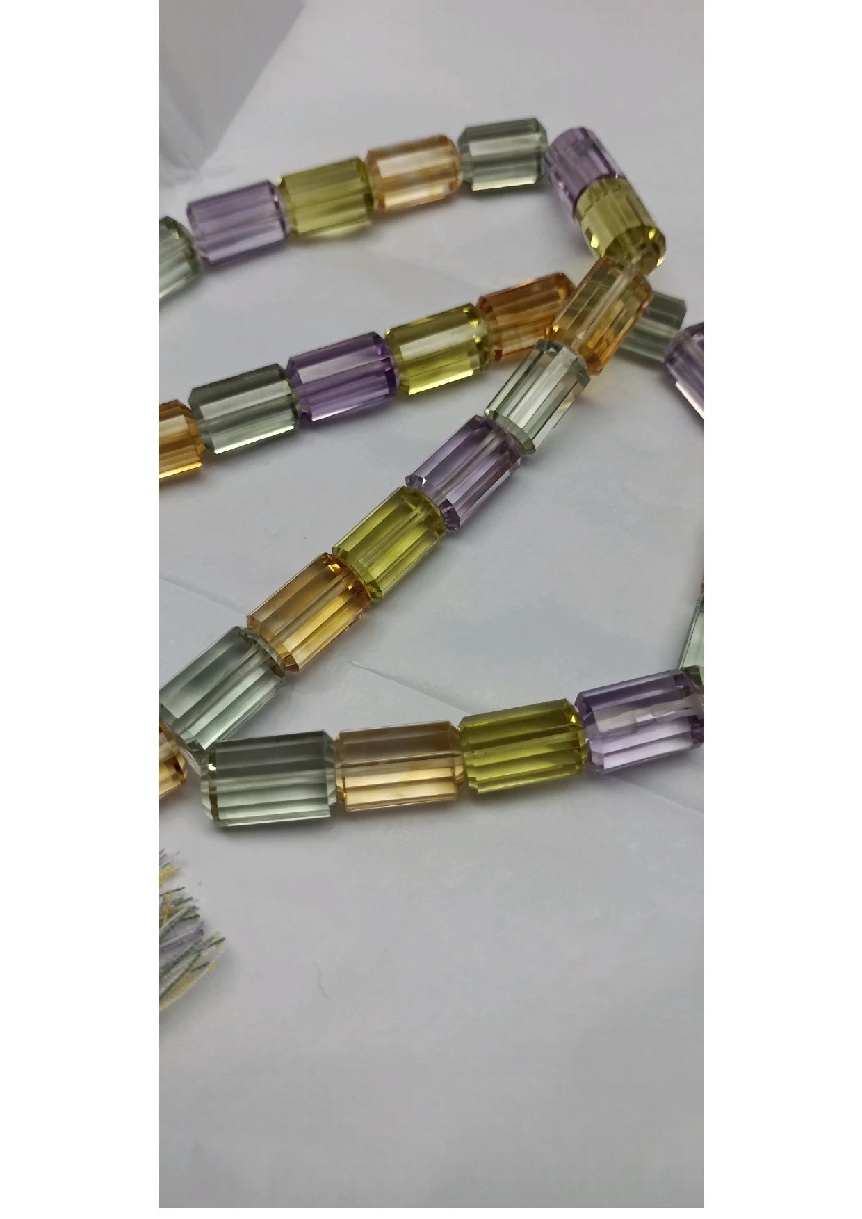 Close-up of faceted cylinder beads on a strand, multicolor green, gold and lavender