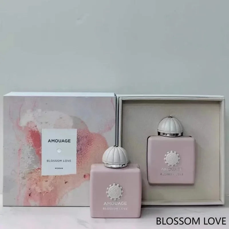 Amouage Blossom Love perfume set with two matte pale pink glass bottles and ornate white caps in a gift box.