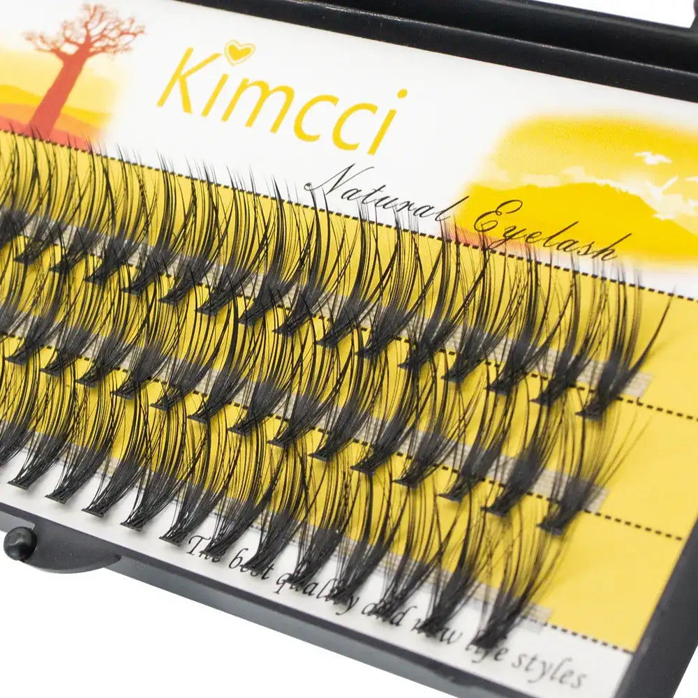 Black individual cluster eyelash extensions arranged on a yellow Kimcci brand tray for natural 3D volume.