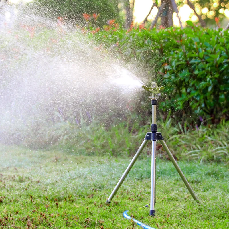 Blue-and-gold rotating tripod sprinkler emitting fine spray water