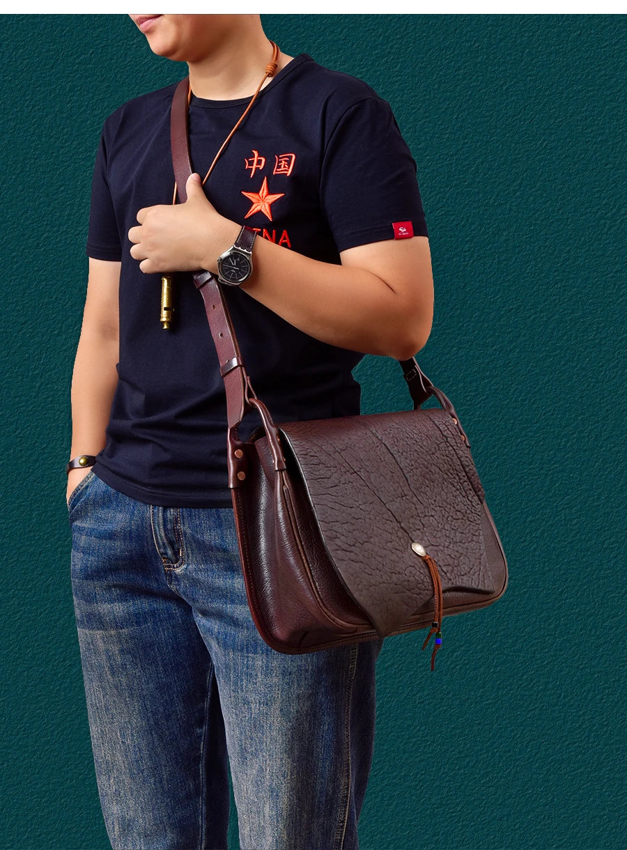 Vintage dark brown genuine cowhide leather messenger bag with textured flap and toggle closure, worn as a shoulder bag.