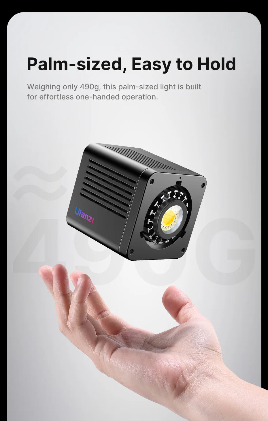 Black, cube-shaped handheld LED video light floating above a hand, featuring a round central light source.