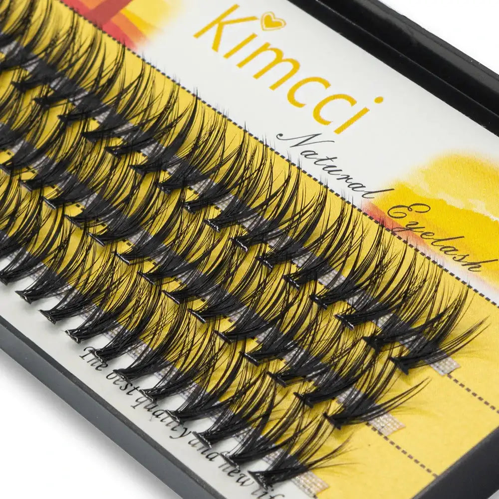 Black, individual mink eyelash extension clusters arranged in rows on a yellow branded tray.