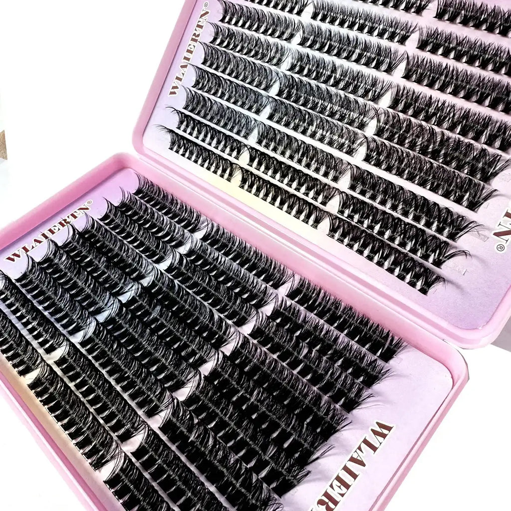 Black individual eyelash extension clusters arranged in a pink plastic storage tray for professional makeup application.