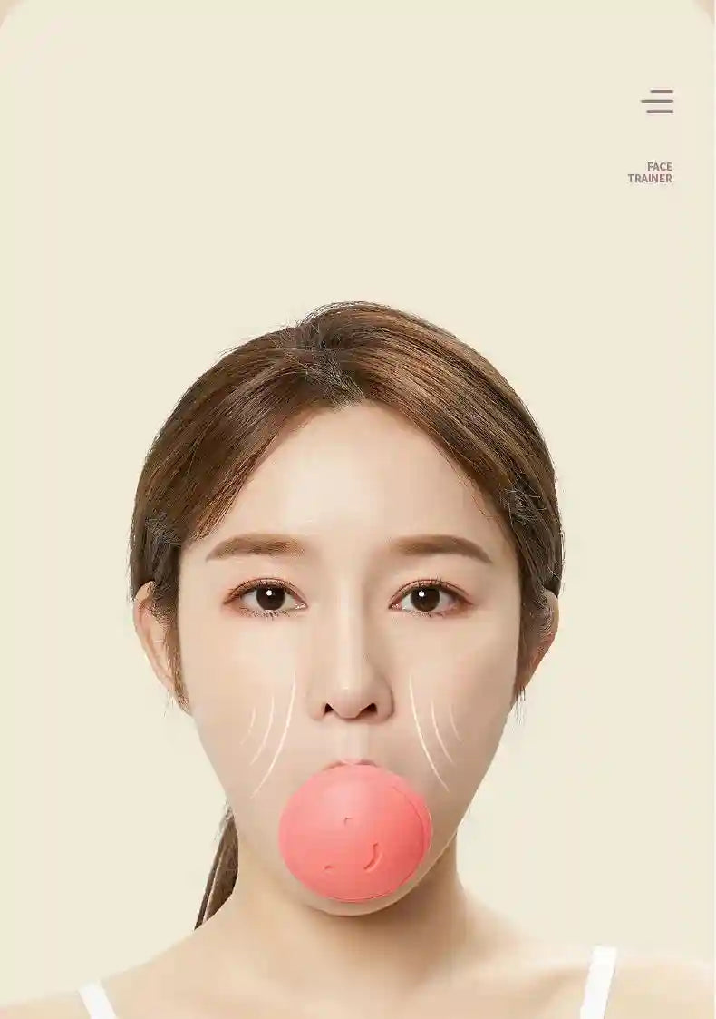 A woman using a round, pink silicone face-slimming exerciser with a smiley face design in her mouth.