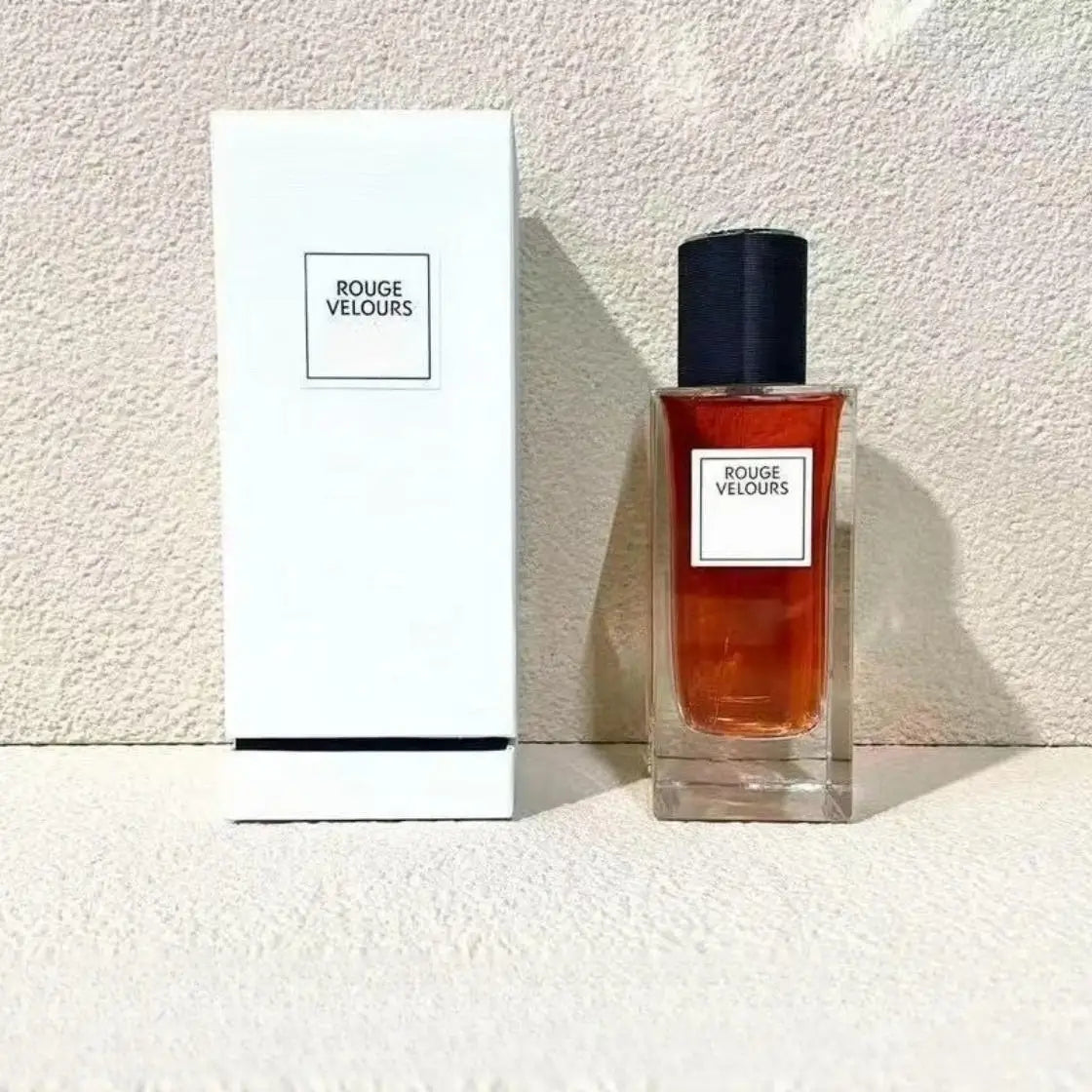 Rouge Velours perfume in a rectangular glass bottle with red liquid and black cap next to a white box.