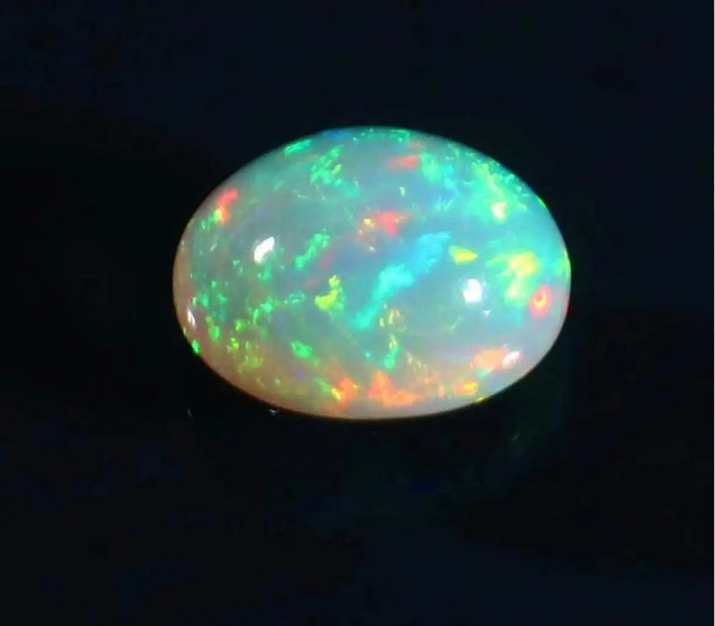 Oval opal cabochon with vivid green-blue fire and orange-red specks