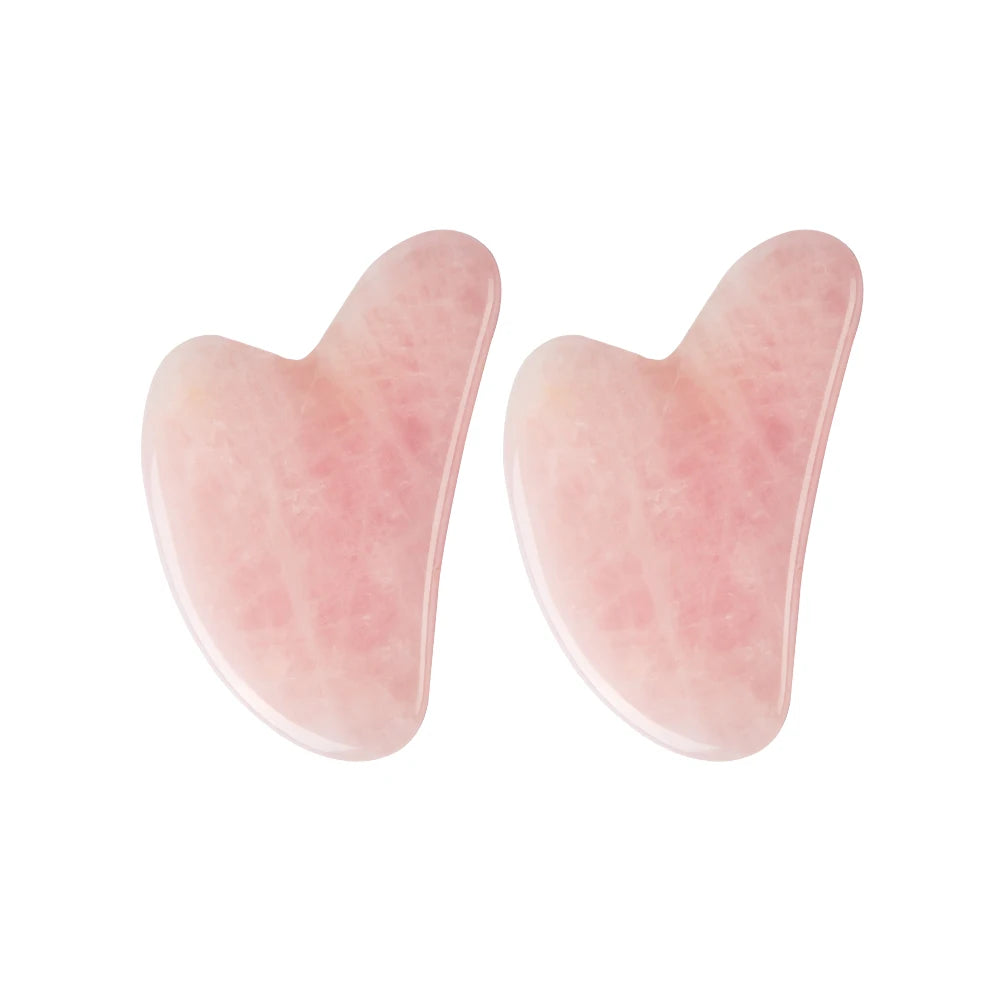 Two heart-shaped rose quartz gua sha facial massage tools with a smooth, polished light pink stone finish.