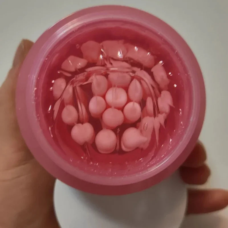 Top-down view of a pink jar filled with clear gel containing small, round pink collagen capsules.