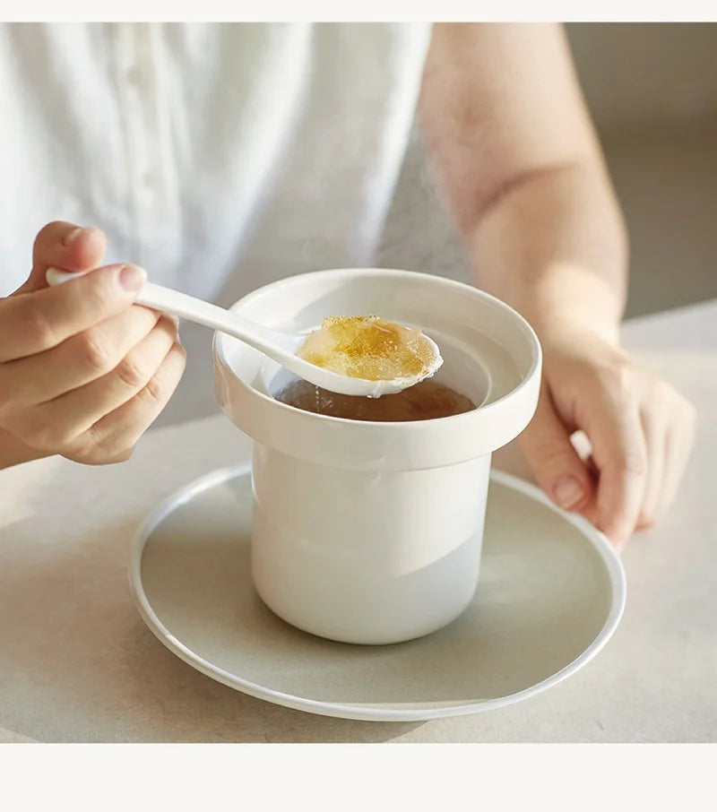 White mini electric cooker with inner bowl on tray, spoon lifting food
