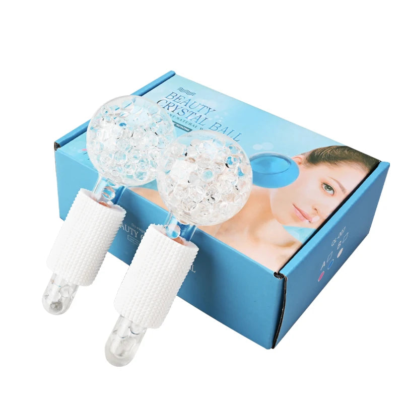 Two clear glass facial massage globes with white textured grips, displayed in front of a blue product box.