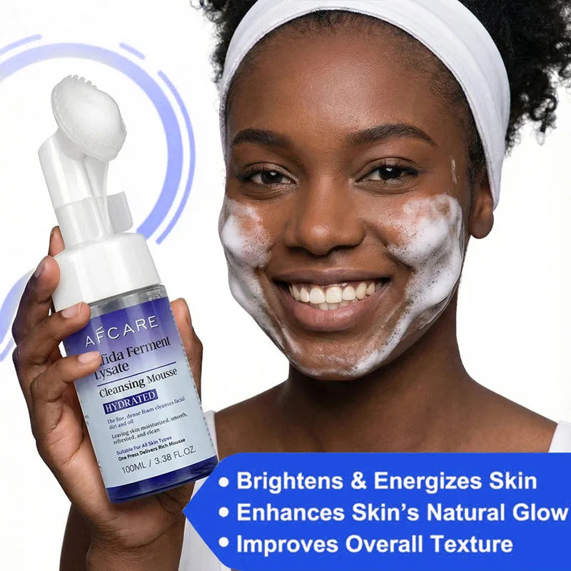 A woman with face foam holding a bottle of AFCARE cleansing mousse with an integrated silicone brush applicator.